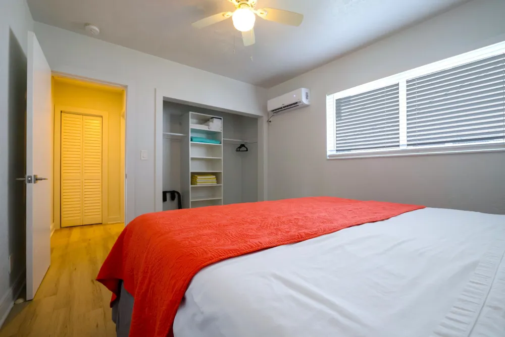 Studio bedroom with coral bedspread and beach painting