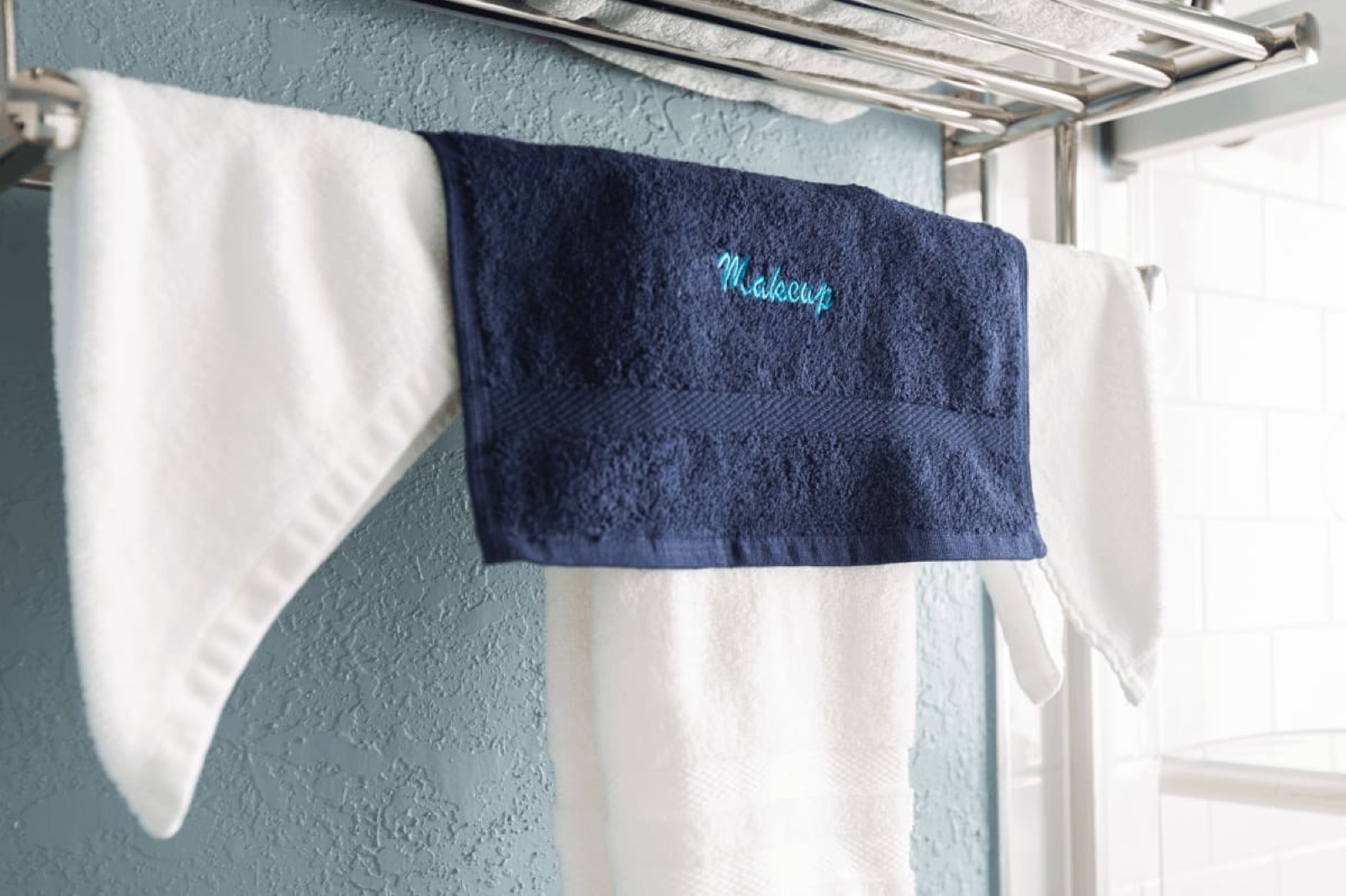 Embroidered navy and white towels on a rack