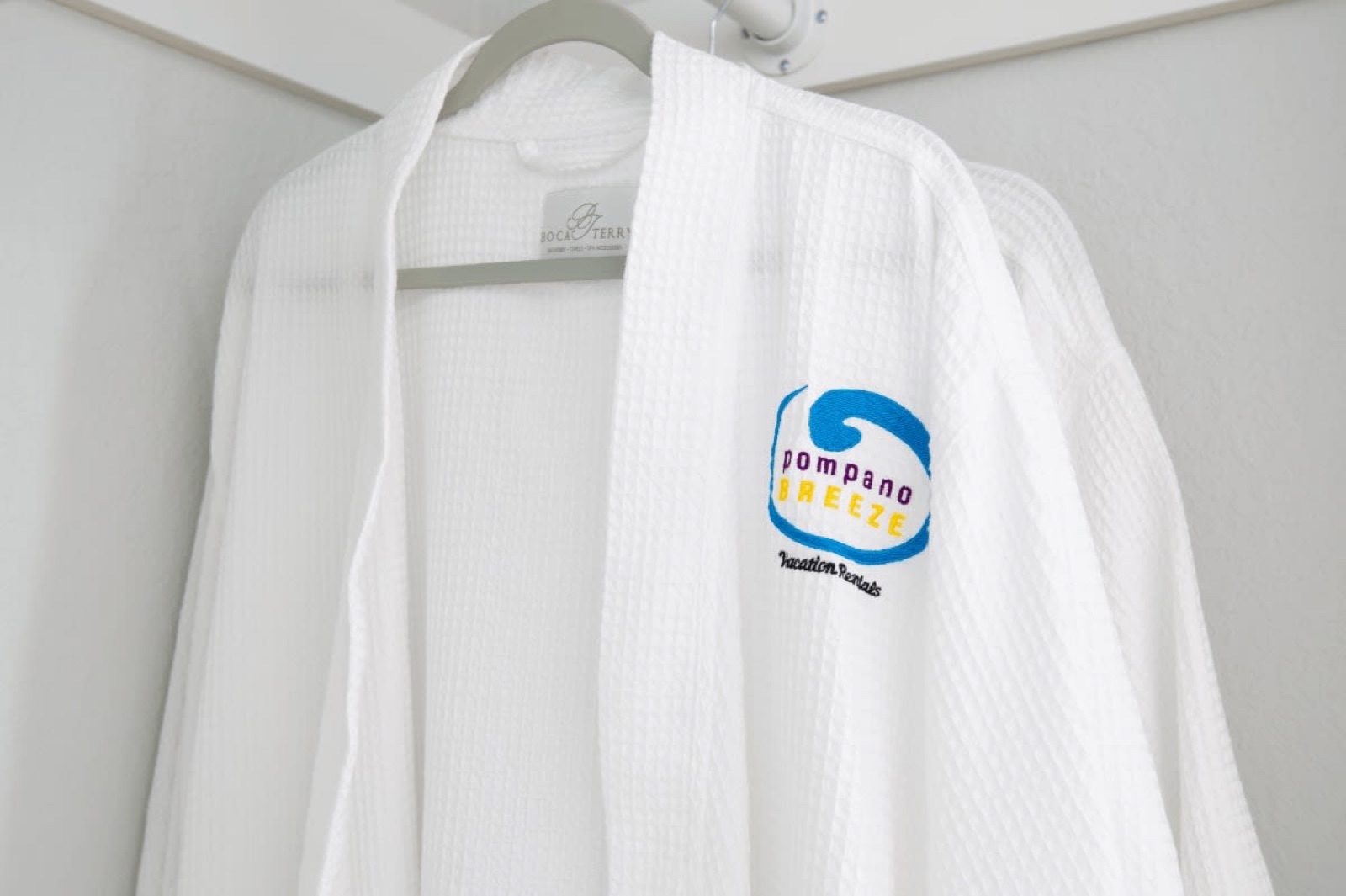 Branded white bathrobe on hanger at Pompano Breeze, Pompano Beach