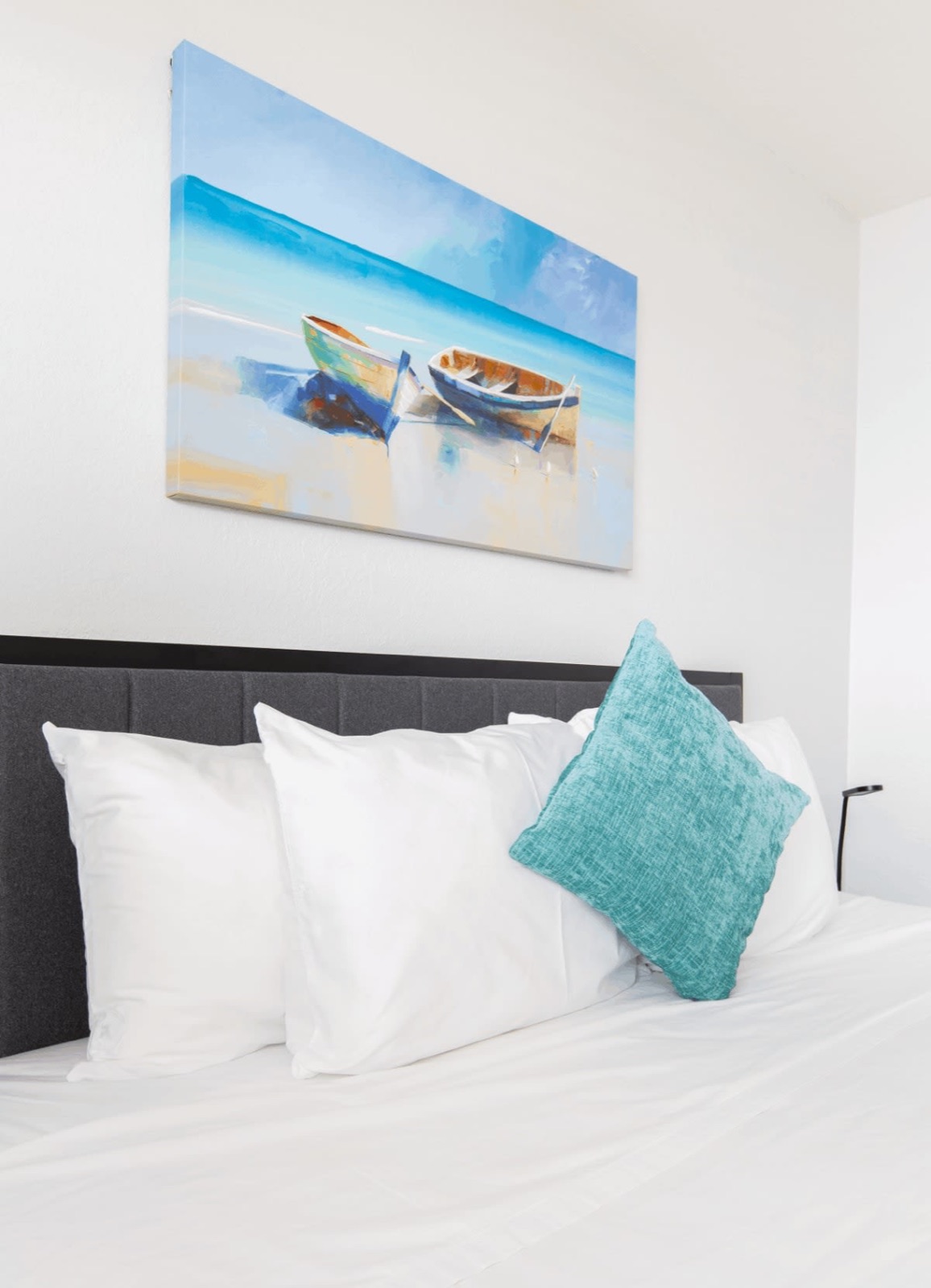 Bed with teal pillow under beach painting, Pompano Beach, FL