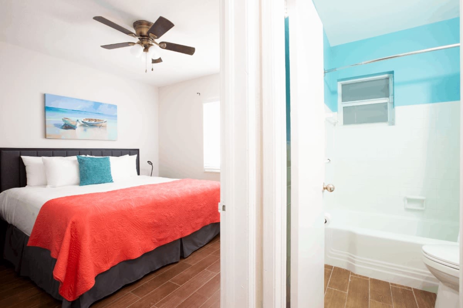 Bedroom with red bedspread and ensuite bathroom at Pompano Breeze, Pompano Beach