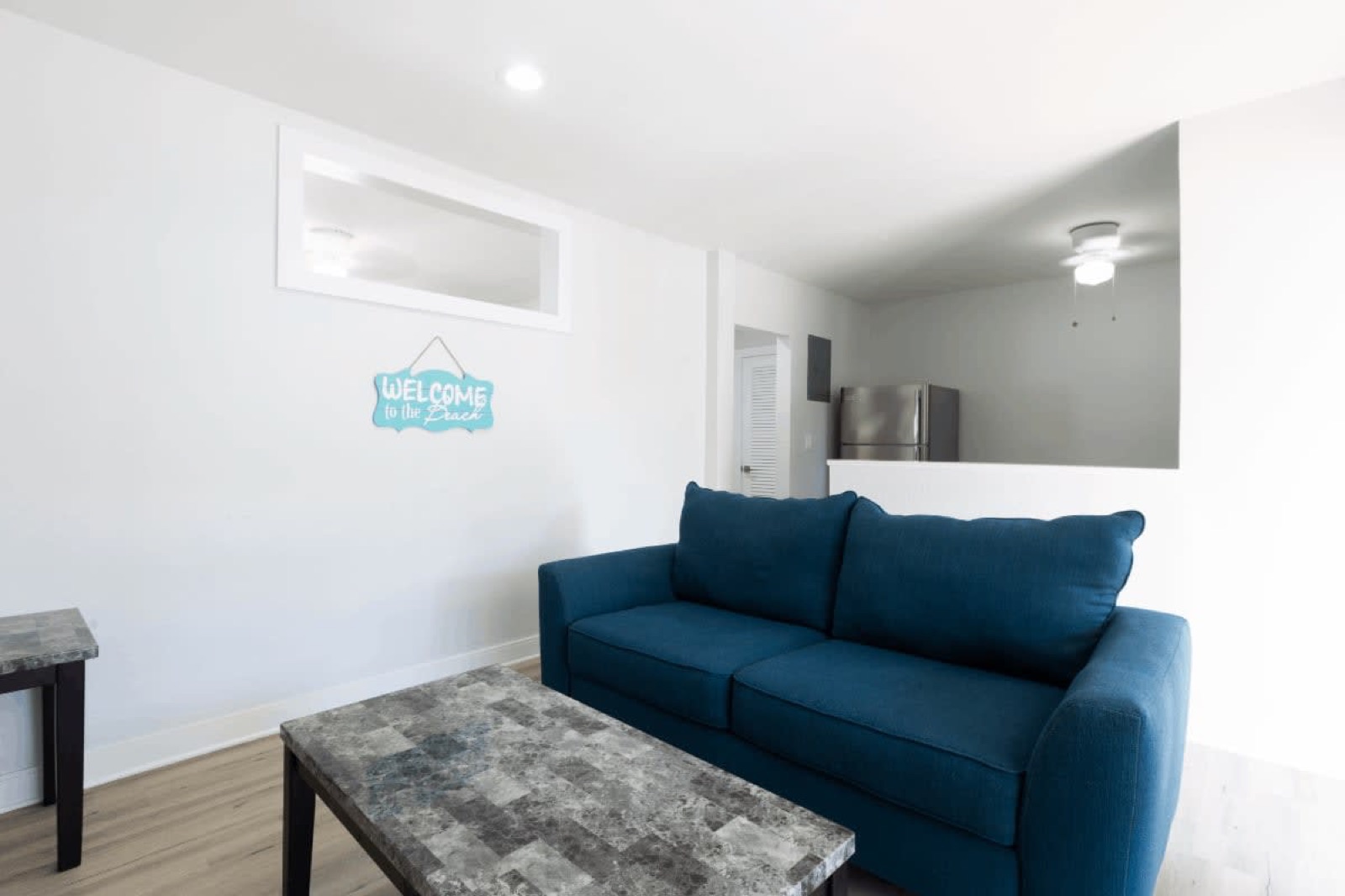 Suite living room with blue sofa and a welcome sign at Pompano Breeze
