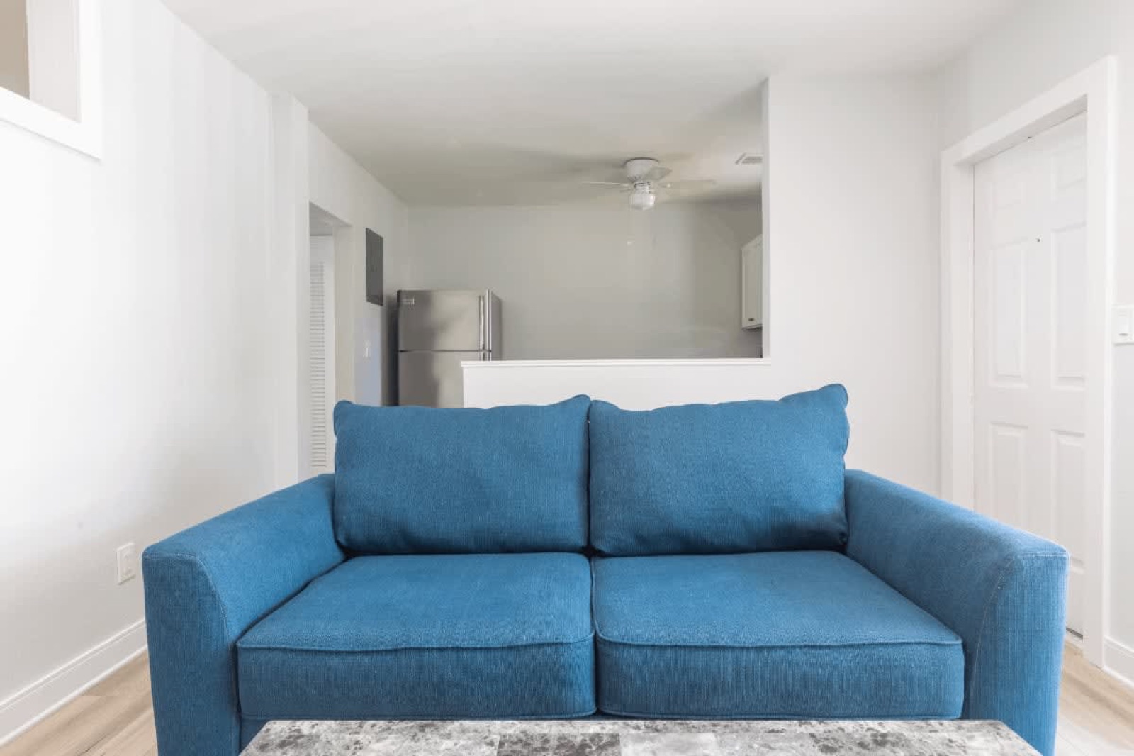 Living room blue sofa and kitchen beyond at Pompano Breeze, Pompano Beach