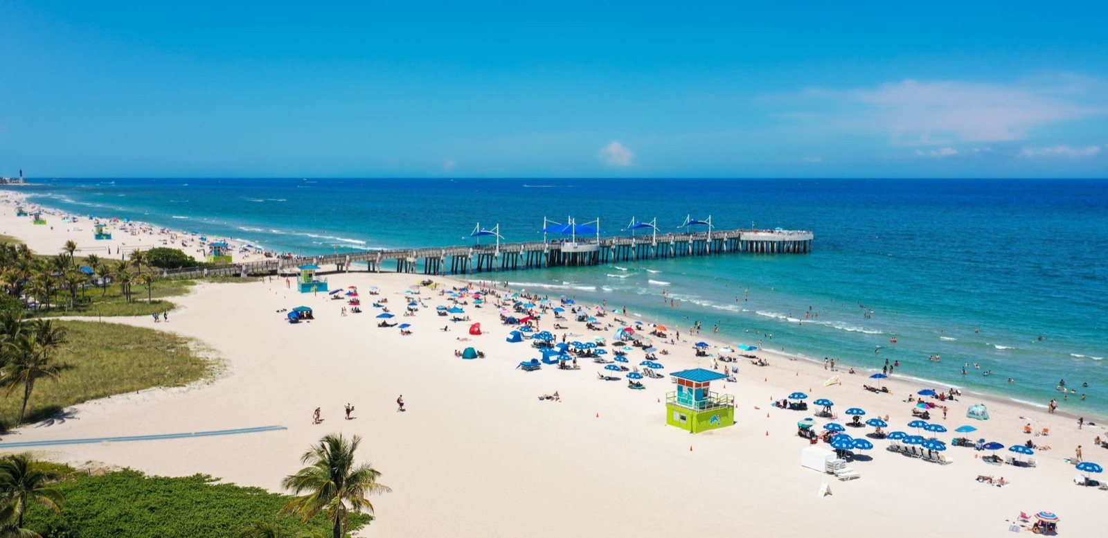 Aerial view of the Pompano Beach pier with beach umbrellas on the sand