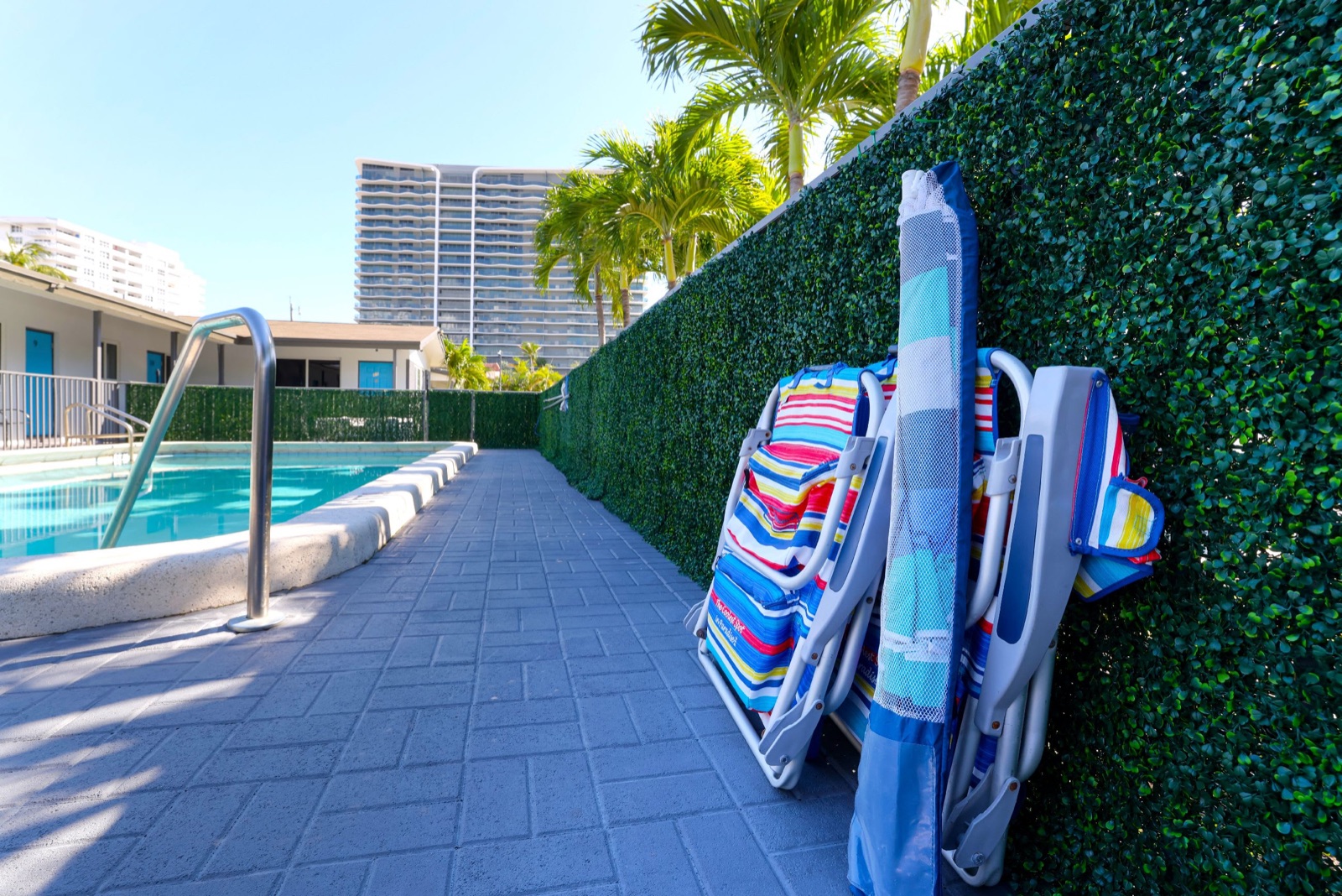Pool deck with beach chairs and an umbrella at Pompano Breeze