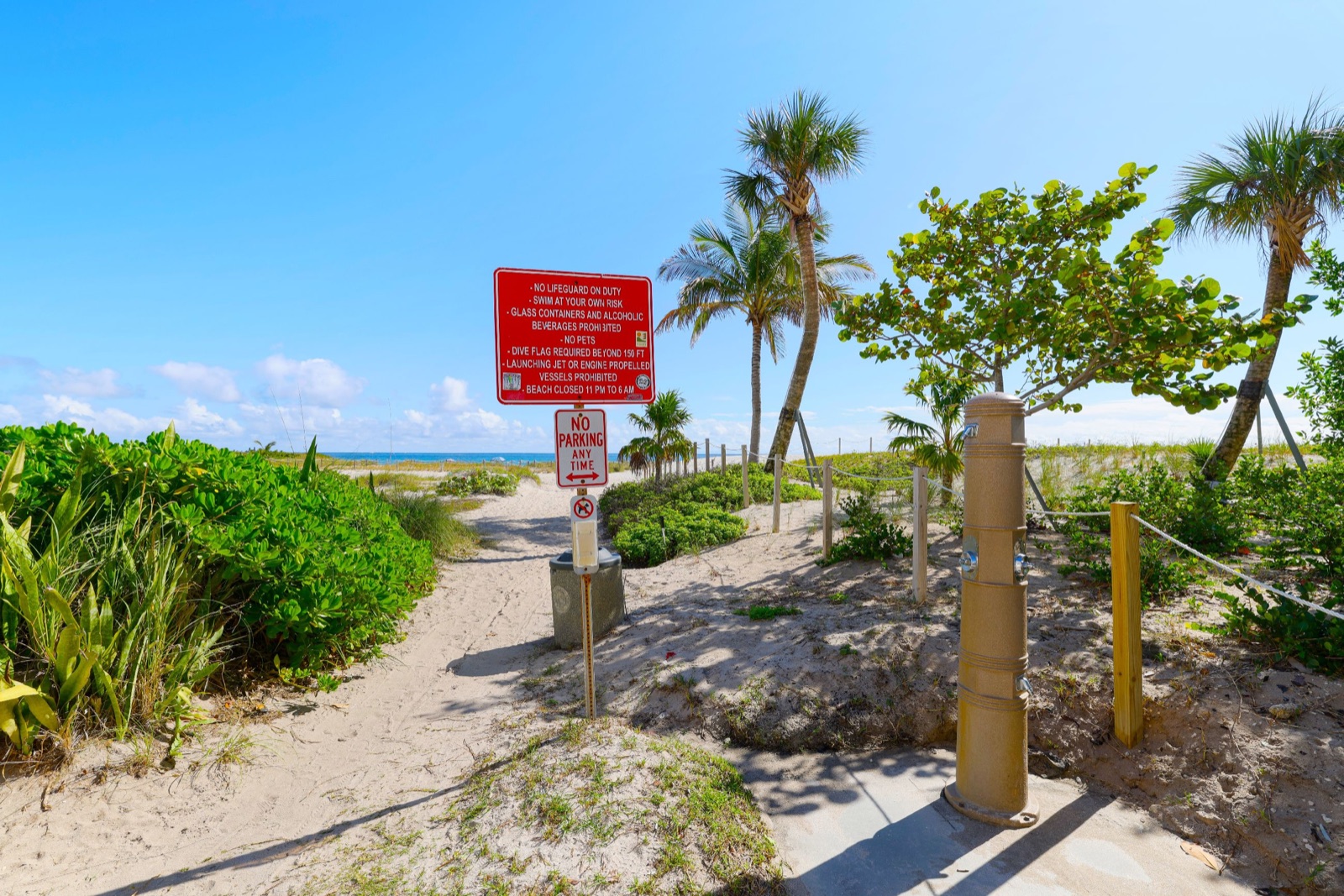 Beach access path with a warning sign leading to the sand