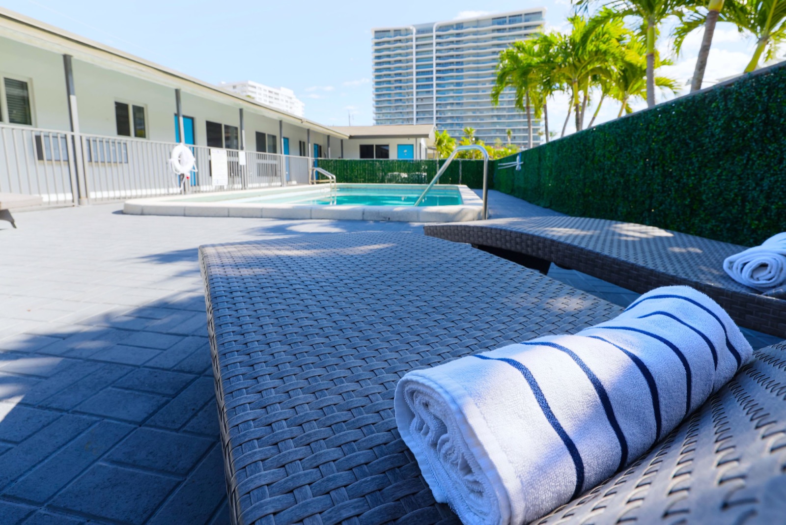 Pool lounger with rolled striped towel at Pompano Breeze, Pompano Beach
