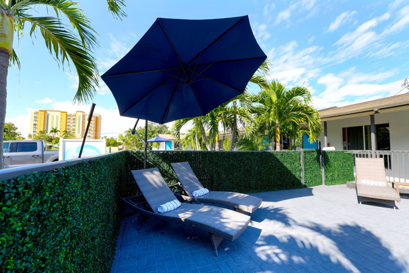 Lounge chairs under blue patio umbrella at Pompano Breeze, Pompano Beach