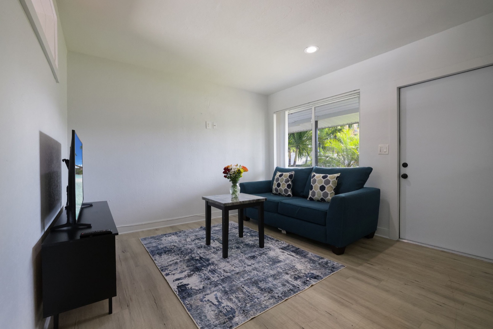 Living room with sofa, flowers and TV at Pompano Breeze, Pompano Beach